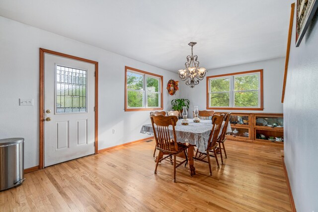 dining room featuring baseboards, a notable chandelier, a wealth of natural light, and light wood-type flooring