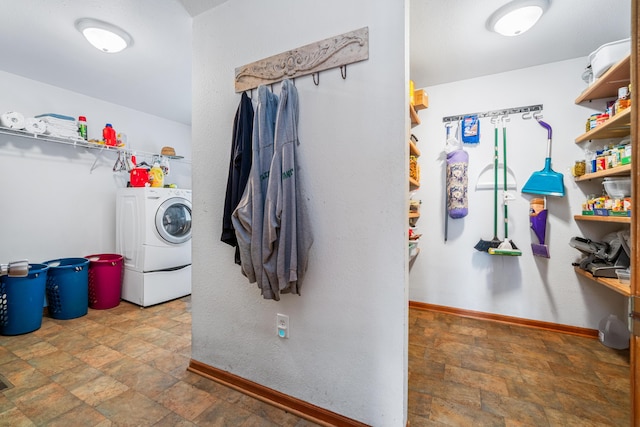 laundry room with laundry area, baseboards, washer / clothes dryer, and stone finish floor