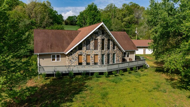 back of property with a yard, stone siding, and a deck