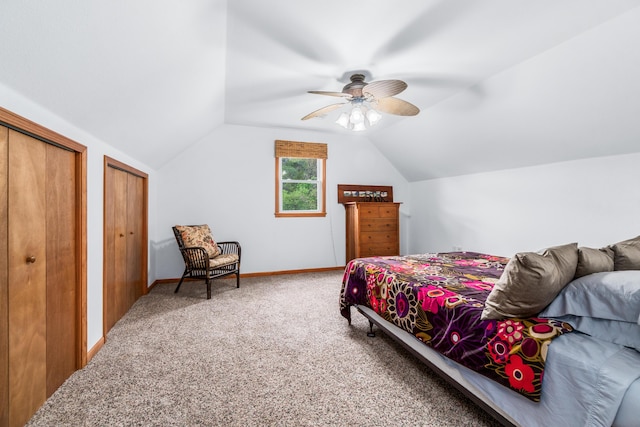 bedroom with ceiling fan, carpet, vaulted ceiling, and two closets