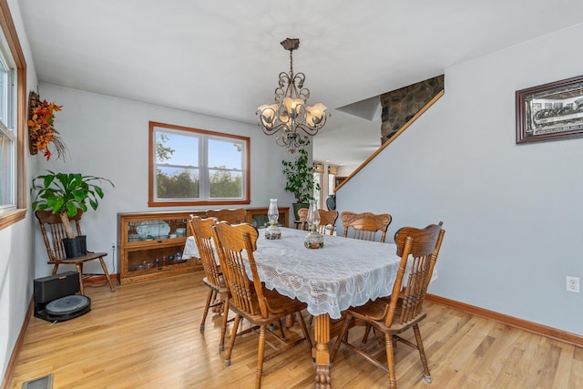 dining space with baseboards, a chandelier, visible vents, and light wood-style floors