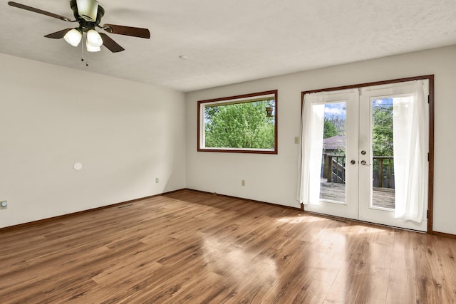 empty room with french doors, baseboards, ceiling fan, and wood finished floors