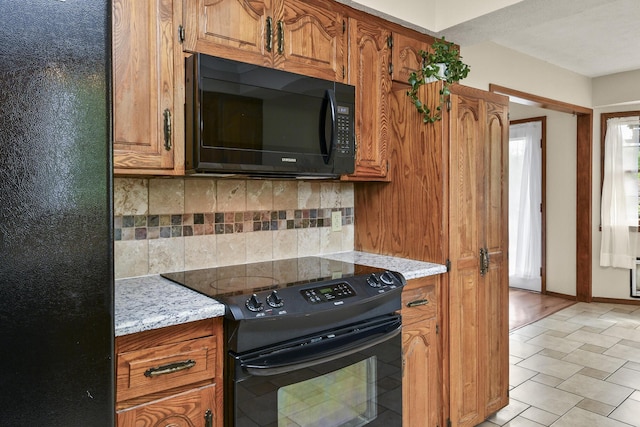 kitchen featuring brown cabinets, black appliances, and tasteful backsplash