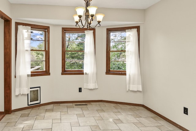 unfurnished room featuring an inviting chandelier, baseboards, visible vents, and a wealth of natural light