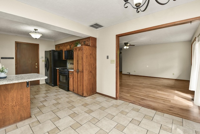 kitchen with brown cabinetry, a textured ceiling, visible vents, ceiling fan with notable chandelier, and black appliances