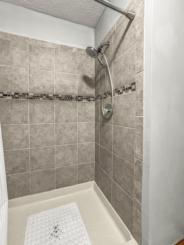full bath with a textured ceiling and a stall shower