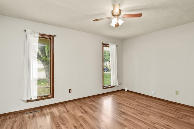 spare room featuring ceiling fan, visible vents, baseboards, and light wood-type flooring