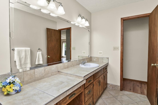 bathroom with tile patterned floors, baseboards, and vanity
