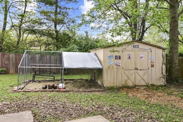 view of outdoor structure with fence and an outbuilding
