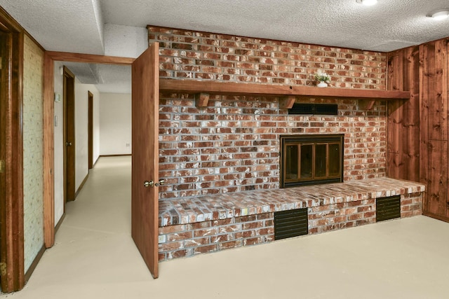 interior details featuring a textured ceiling, wooden walls, and a fireplace