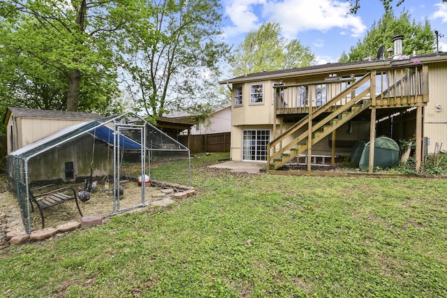 rear view of property featuring an outdoor structure, exterior structure, fence, stairs, and a yard