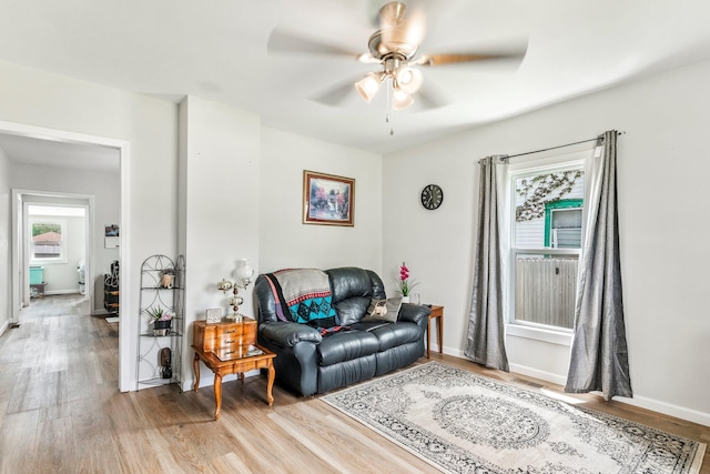 living room with visible vents, a ceiling fan, light wood-style flooring, and baseboards
