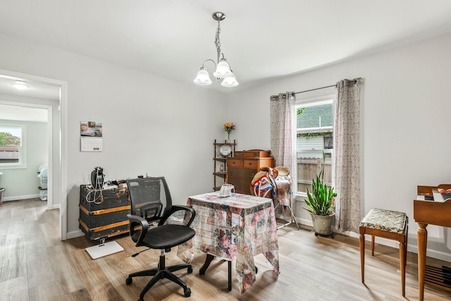 office area with light wood-style floors, baseboards, and an inviting chandelier