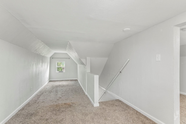 additional living space with carpet floors, baseboards, and vaulted ceiling