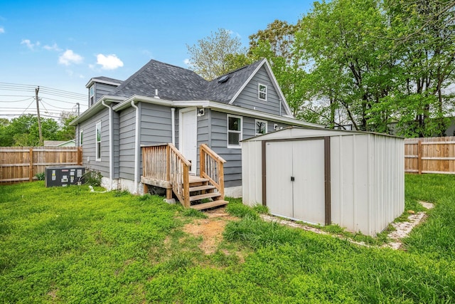 rear view of property with a lawn, a storage shed, and a fenced backyard
