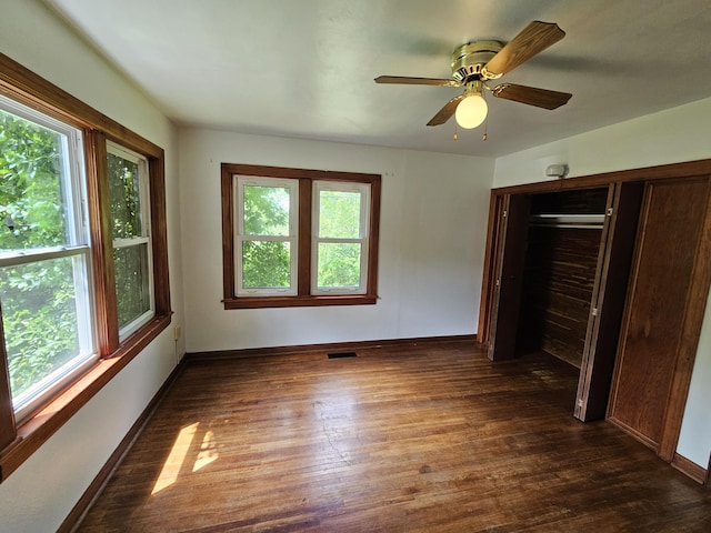 unfurnished bedroom with a ceiling fan, visible vents, baseboards, a closet, and dark wood-style floors