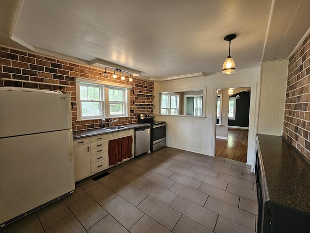kitchen with stainless steel appliances, dark countertops, a sink, and a healthy amount of sunlight