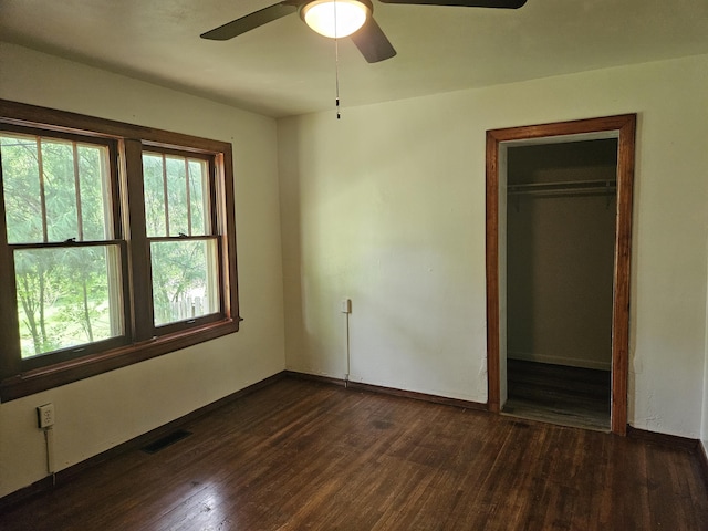 unfurnished bedroom featuring dark wood-style flooring, baseboards, visible vents, and a closet