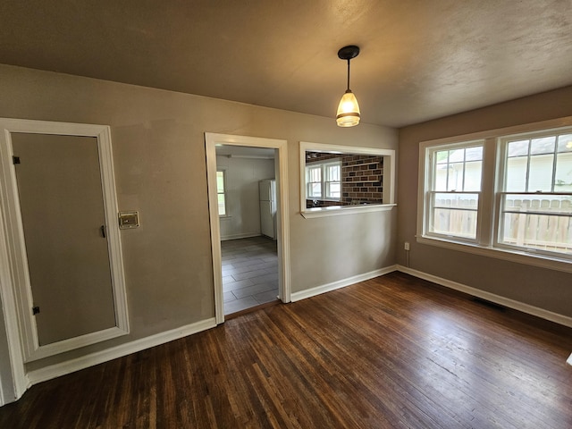 unfurnished dining area featuring baseboards, visible vents, and dark wood-style floors
