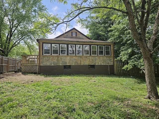 back of property with fence, a yard, and a deck