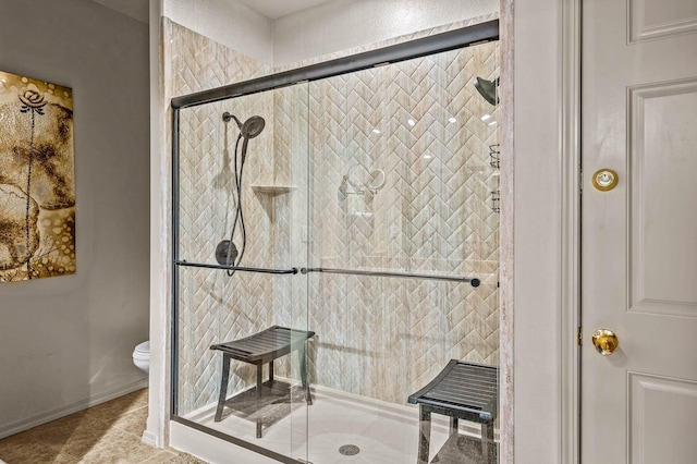 bathroom featuring tile patterned flooring, baseboards, a stall shower, and toilet