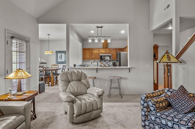 living area with baseboards, a high ceiling, light carpet, and visible vents
