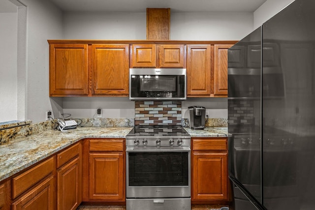 kitchen with brown cabinetry, light stone countertops, and stainless steel appliances