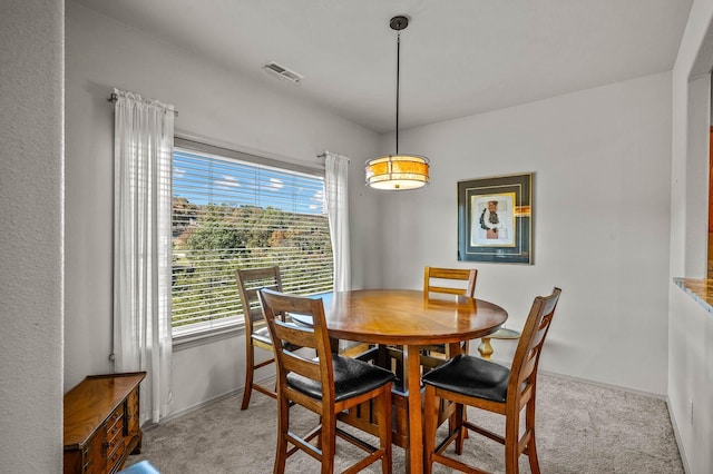 dining space featuring baseboards, visible vents, and light colored carpet