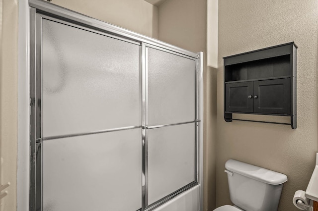 bathroom with toilet and bath / shower combo with glass door