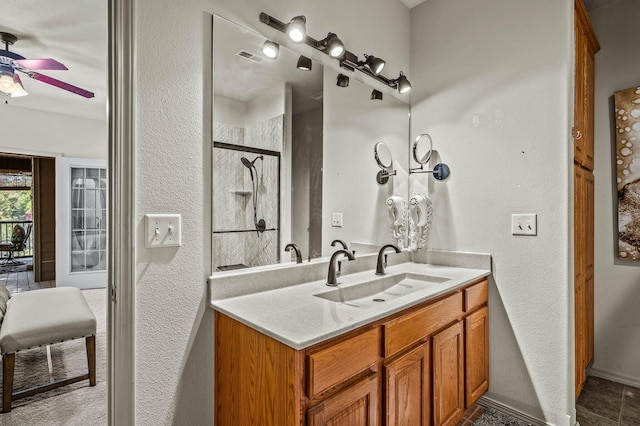 bathroom featuring vanity, a ceiling fan, a textured wall, and tiled shower