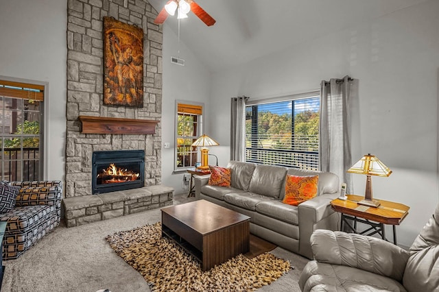 carpeted living room featuring a ceiling fan, high vaulted ceiling, visible vents, and a stone fireplace