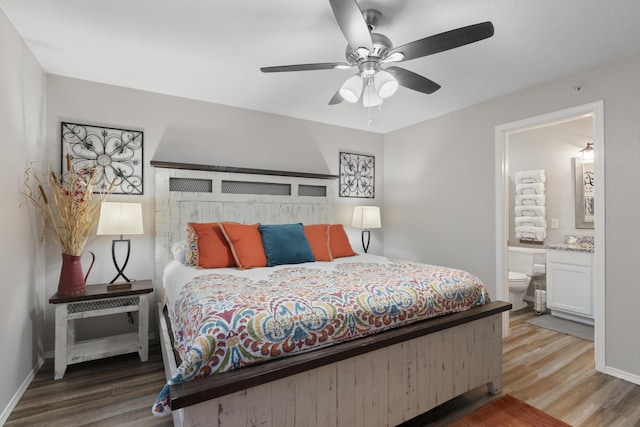 bedroom featuring baseboards, ensuite bath, and wood finished floors