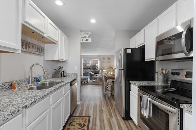 kitchen featuring white cabinets, appliances with stainless steel finishes, a sink, and light wood-type flooring