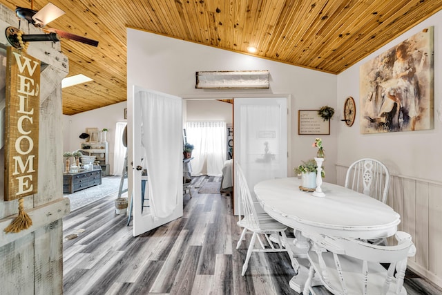 dining space featuring wood finished floors, wood ceiling, lofted ceiling, and a wainscoted wall