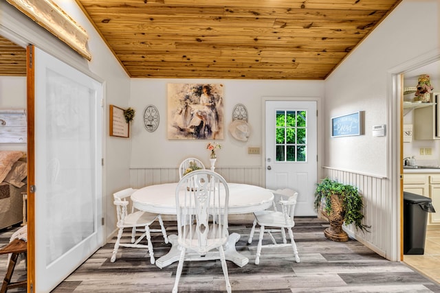 dining space with wooden ceiling, a wainscoted wall, wood finished floors, and lofted ceiling