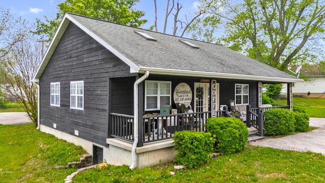 view of front of property with roof with shingles, a porch, and a front yard