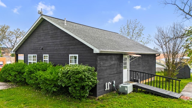 view of home's exterior with a lawn and roof with shingles