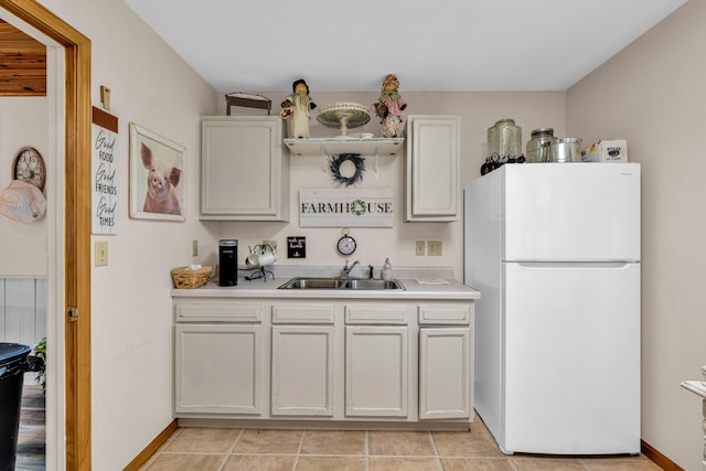 kitchen with freestanding refrigerator, light tile patterned floors, a sink, and light countertops