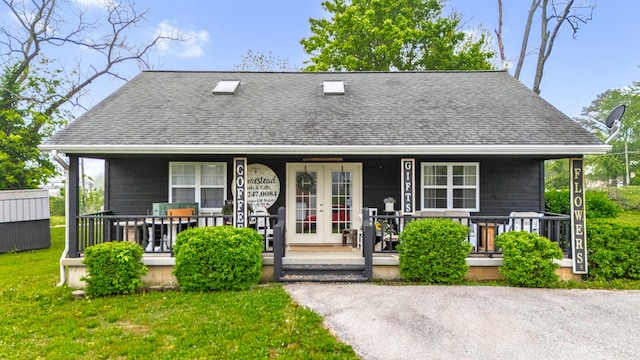 view of front facade featuring french doors, a shingled roof, a porch, and a front yard
