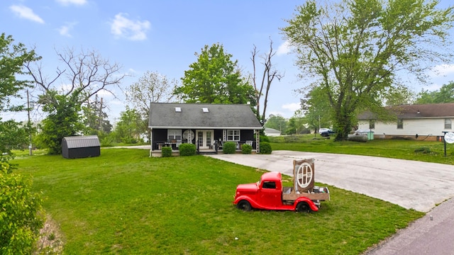 exterior space featuring a front lawn, an outbuilding, and driveway