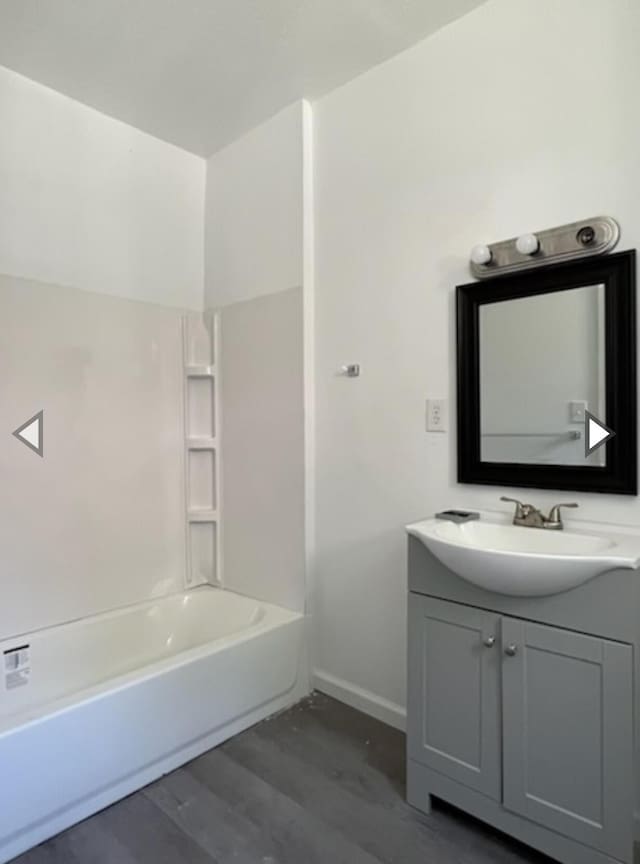 bathroom featuring vanity, shower / bathtub combination, baseboards, and wood finished floors