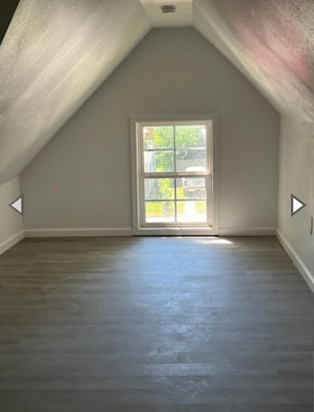 additional living space with baseboards, a textured ceiling, dark wood finished floors, and lofted ceiling