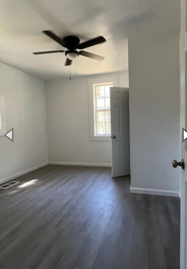 spare room featuring baseboards, a ceiling fan, dark wood-style flooring, and visible vents