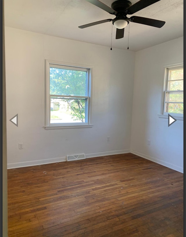 spare room featuring a healthy amount of sunlight, wood-type flooring, and visible vents