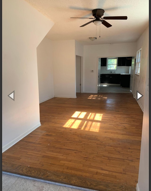 unfurnished living room featuring baseboards, ceiling fan, hardwood / wood-style flooring, and a textured ceiling