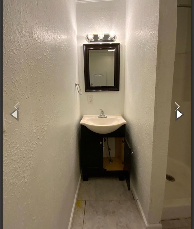 bathroom with vanity, baseboards, a shower stall, and tile patterned floors