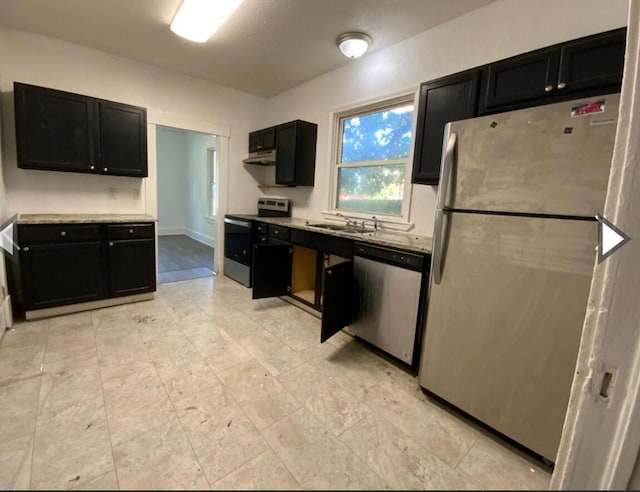 kitchen with stainless steel appliances, dark cabinets, and a sink
