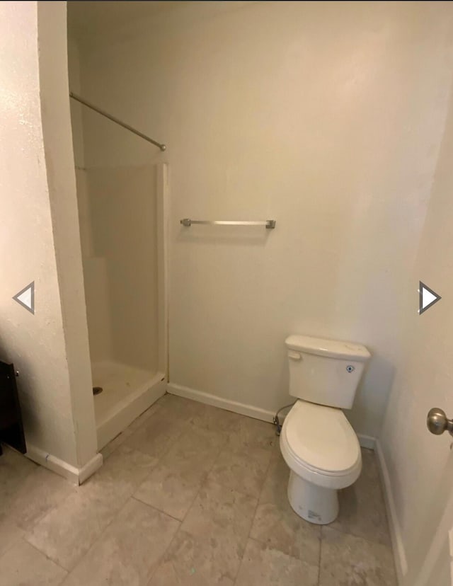 bathroom with baseboards, tile patterned floors, toilet, and a shower stall