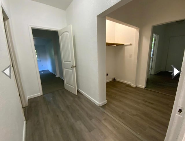 corridor featuring baseboards and dark wood-style flooring
