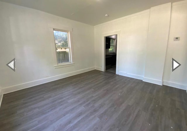 unfurnished room with baseboards and dark wood finished floors